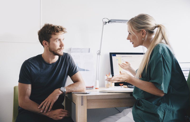 Man listening to female doctor in office