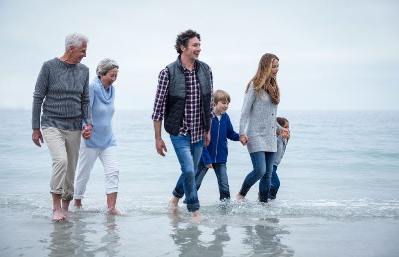 Family in various stages of life walking on seashore