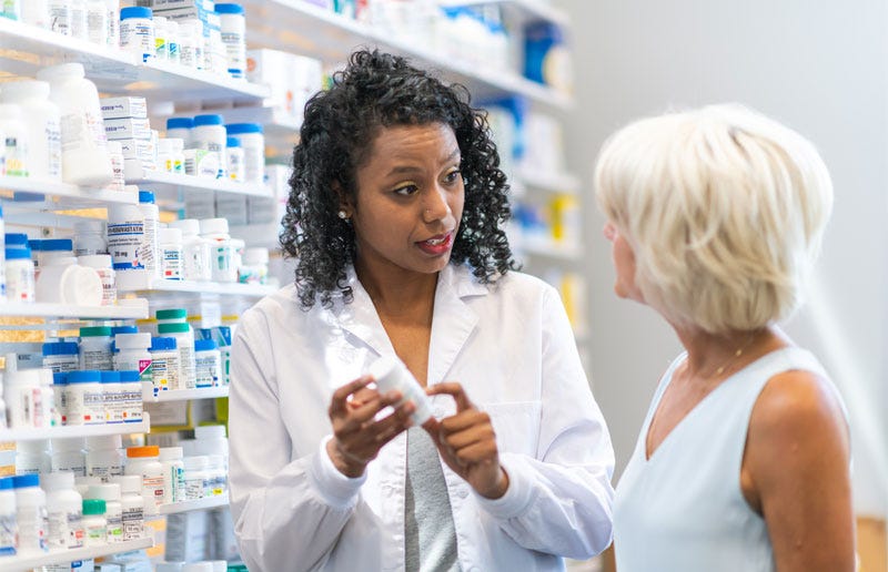 Practitioner in front of supplement shelf, advising patient on which products to purchase