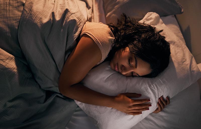 High-angle shot of a young woman sleeping in her bed at home during the night